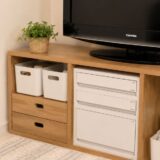 Organized TV stand storage in a small Japanese apartment using simple white bins and drawer organizers
